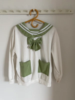Grön sjömanströja med kaninöron på baksidan 🍃 - Söt krämvit/ grön sjömanströja med kaninöron & rosett , köpt på Tradera. Använd ungefär två gånger. Gjort i stretchigt bomullsmaterial. 