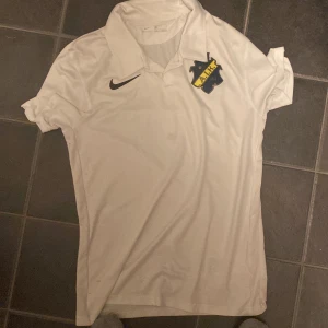 En vit AIK tröja. - En vitt AIK tröja. Jätte skön att ha på sig. Det är en DRI-FIT tröja. Den har små små håll på ryggen så att man inte svettas på sommaren.