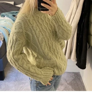 Grön stickad tröja  - En grön stickad tröja men kabelstickat mönster i. Verkligen hur fin som helst!!  Hör av dig vid frågor eller fler bilder ( Köparen står för frakten)