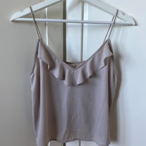 Linne med volang - Linne med volang. Färgen är lite grå/beige. Storlek: XS. Fint skick. Köparen står för frakt, går bra att samfrakta med annat.