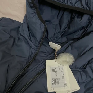 Jacka - En helt ny och oanvänd marinblå lång jacka i storlek 40 som köptes för 1300 Kr. Den säljs nu för 650 Kr men pris kan alltid diskuteras. Skriv privat för fler bilder just eftersom man inte kan få med en helbild på hela jackan. 