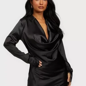 Satin dress (S) - NELLY  - Helt oanvänd svart satinklänning från Nelly med prislapp kvar i strl. 36. En perfekt svart liten klänning med långa ärmar och en djup och stor urringning. Aldrig kommit till användning. 