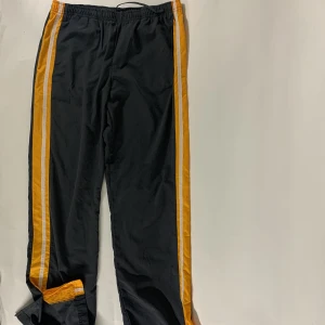Nike trainings byxor från 90tals.  - Nike trainings byxor från 90tals. Grå och orange med vits mesh. ”Mini swoosh” längst ner på ben. 