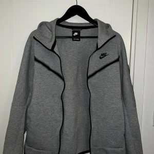 Nike Tech Fleece Kofta Grå - Grå Nike Tech Fleece kofta i nyskick. Då nypris ligger på 1000+ kr är detta ett väldigt generöst pris. Först till kvarn!