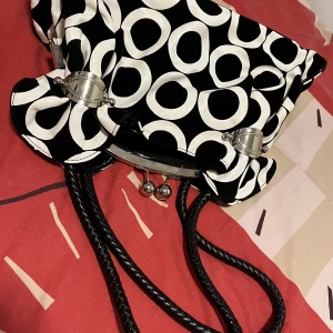 En spansk väska  - Svart och vit, mönstrad väska med många fickor. Mycket bra skick, nästan oanvänd. Skickar fler bilder vid behov 