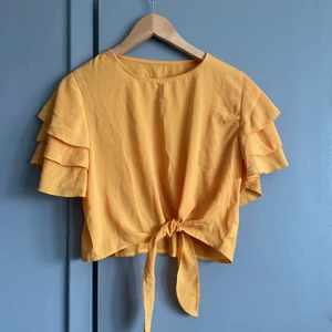 Magtröja - Senapsgul magtröja med volang i ärmarna och knytning i midjan. Stl L men passar även M