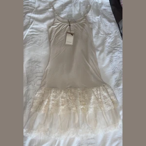 Långt linne med spets nedtill - Långt linne från fina märket Cream med spets vid nedtill. Superfint att ha under en kort kjol eller klänning.😍 Helt nytt med tags kvar. 40kr+frakt
