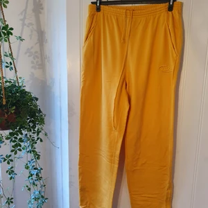 Mjukisbyxor gula FILA st XL - Bekväma mjukisbyxor med dragkedja längst ner. Märket är FILA och plagget blir så unikt och självständigt med den gula färgen. Högmidjade.