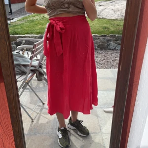 Röd långkjol - Långkjol från and Other stories med band i sidan som man antingen kan byta runt magen med eller göra en rosett i sidan