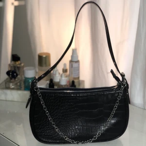 SVART VÄSKA MED SILVERKEDJA - En lite ”tuffare” baguette - bag i svart med en fin silverkedja som detalj (Går även att göra osynlig och stoppa i den i väskan). Använd enstaka gånger. 