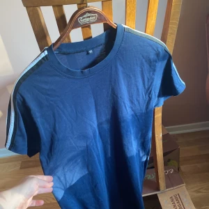 Adidas t-shirt - Mörkblå, T-shirt med adidas sträck på båda axlarna. Storlek XS men passar M perfekt och även slim fit i L. Nyskick