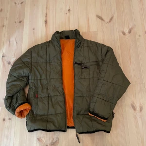 Bomberjacka  - Mörkgrön bomberjacka med organe foder. Fickor fram och bak. Passar som oversized för dig som normalt har xs-m. 