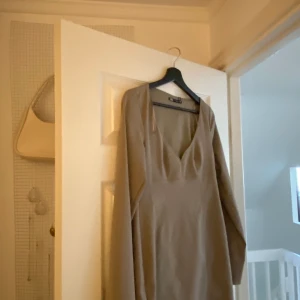 Kort klänning, beige Zara - Kort klänning med fräck utigning, perfekt med ett par höga boots. Nyskick, etiketten på. Säljes pga, jag har flera liknande, även i liknande färg. BEIGE/BRUN! UTSÅLD PÅ SIDAN! 