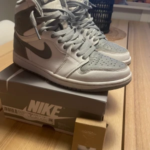 Air Jordan 1 Retro High OG  strl 6 / 40/ 25 cm - Säljes ett par superfina high retro. Grå/ vit Storleken blev för liten. Använda max några ggr endast. Köpta på SNS. Kvitto finns. Skokartong med extra skosnören ingår även. Strl , se bild av skolåda. 