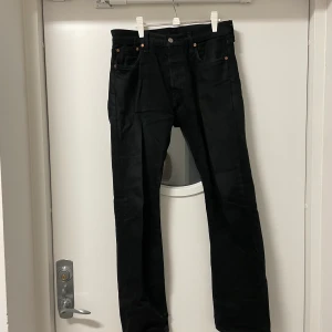 Levi’s 501 Jeans Svarta - Jag säljer nu ett par svarta Levi’s 501 Jeans, de är köpta på Levi’s hemsida för omkring 1 100kr. De är i generellt bra, men använt skick. Det finns ett litet hål vid slutet av ena benet, men det är enkelt att sy ihop. Några av sömmarna slitna. 
