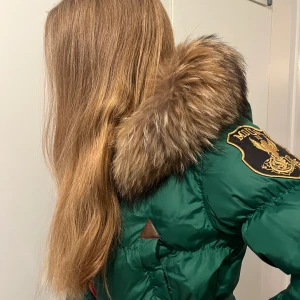 Grön dunjacka stl M/38 - Snygg figursydd dunjacka med härlig päls. Stora bra fickor.  Litet skav på en skin imitation på framsidan. Kan skicka bild vid intresse.