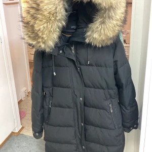 Lång damjacka HOLLIES - Jackan är i mycket bra skick! Säljer den pga viktnedgång. Den är mycket varm!Pälsen är 100% äkta! Kvitto kan skickas om man vill! Jackan är köpt för ca 5000kr på jackan.com. Den h använts i endast en vinter sen har den mest legat i garderoben och hängt!