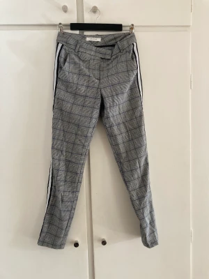 Gråmönstrade byxor - Coola byxor i stil som kostymbyxor men med en mer sportig look. Mönster av grått och mörkblått samt vit/svart rand längst sidan. 