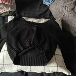 En svart ”V” ringad stickad tröja som är croppad