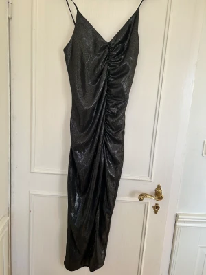 Glittrig festklänning med slits - Jag säljer denna helt nya klänning med slits ifrån NA-KD, perfekt till fest eller middag. Klänningen har kvar prislappen och är aldrig använd.