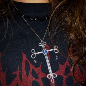 Kors av härdat stål - Kors som jag har gjort av härdat ståltråd med en ljusblå glaspärla i mitten, plus små detaljer som hänger :) eftersom den är handgjord så kommer den kosta 80kr, sedan 14kr frakt som vi kan dela på ;D 