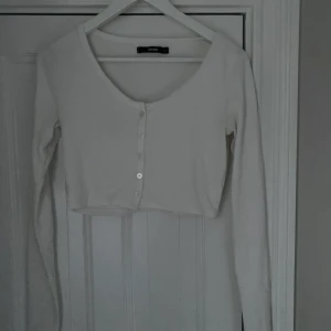 Vit långärmad tröja  - En vit långärmad tröja med knappar på. Mycket fin och inte använd alls mycket. En basic tröja som man kan ha till mycket olika underdelar. Tröjan är från bik bok. Frakt står köparen för