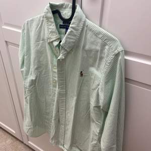 Grönvit randning skjorta från Ralph Lauren i storlek 10 motsvarar 36/38. Är en Classic Fit. Nyskick, knappt använd. 