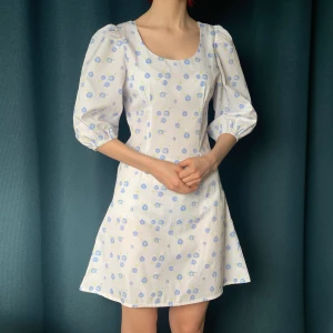 Blommig klänning - Så himla fin vit klänning med söta blå blommor och puffärmar🫶 Använd 2 gånger så den är i nyskick. Hör av dig vid frågor!