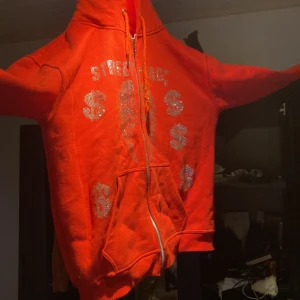 Rhinestone hoodie streat tag - Knappt använd rhinestone Zip hoodie säljer den för jag behöver pengar men den är bra skick och bra passform orginal pris är 600 kr