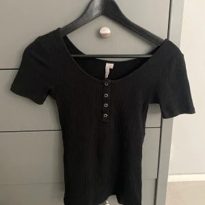 Tröja - Svart ribbad tröja med knappar. väldigt stretchig och bekväm. Använt få tal gånger. Ordinarie pris 150kr och säljer den för 50kr plus frakt.