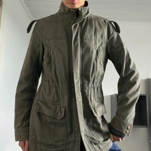 Jacka  - Varm och härlig mossgrön höst/vinterjacka. Fickor till detaljer och något längre vilket värmer extra. 