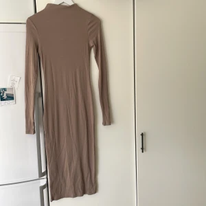 Lång figurnära klänming - Lång figurnära klänning från H&M, sitter jättefint på kroppen. Har även en jättefin detalj med hål för tummen. Möts helst upp i Stockholm men kan även fraktas för en fraktkostnad 🥰