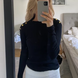 Svart tröja - Fin tröja i fint skick, då den bara är använd Max 2 gånger! Ger en lyxig känsla med de guldiga knapparna på axlarna💕