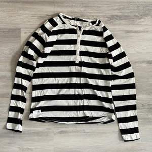 En randig tröja i färgerna svart och vitt med knappar, storleken är XL men passar som M/L