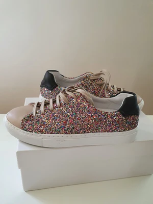 Sneakers i läder, glittriga, helt nya, &other Stories strl 39 - Helt nya aldrig använda sneakers i äkta läder även på insidan. strl 39 från & Other Stories. De är beige med glitter i multicolor samt svarta på hälen. Sköna, helt nya. Nypris 1100kr. 