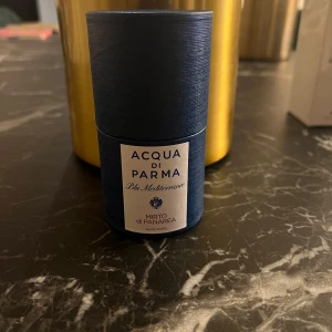 Acqua di Parma Blu Mediterraneo Mirto di Panarea - Säljer en elegant parfym från Acqua di Parma, Blu Mediterraneo Mirto di Panarea. Flaskan är i en djupblå färg med en stilren etikett. Doften är inspirerad av Medelhavet och ger en fräsch och upplyftande känsla. Perfekt för den som älskar en touch av lyx i vardagen.