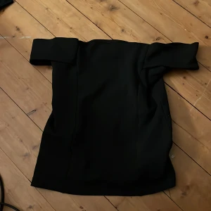 Svart offshoulder topp - Snygg svart offshoulder topp i en stilren design. Perfekt för en kväll ute eller en speciell tillställning. Toppen  har en elegant passform som framhäver axlarna.