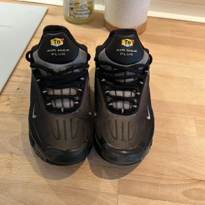 Svarta Nike Air Max Plus - Säljer ett par svarta Nike Air Max Plus med snygg design och bekväm passform. Skorna har en robust sula och klassisk snörning. Perfekta för både stil och komfort.
