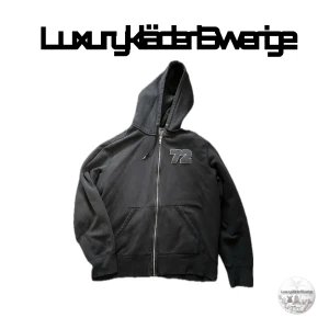  hoodie från Nike vintage zip - Säljer en svart hoodie från Nike med dragkedja och en broderad siffra '72' på bröstet. Hoodien har en klassisk design med långa ärmar och en justerbar huva. Perfekt för en avslappnad stil. Vitage 