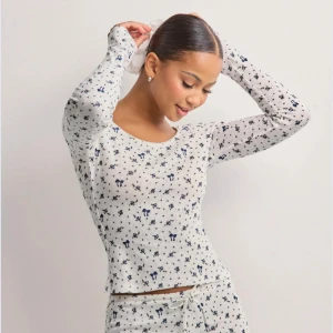 Pyamas tröja från nelly - Säljer en söt vit långärmad tröja med ett blått mönster av små djur och stjärnor. Tröjan är perfekt för mysiga dagar hemma. 