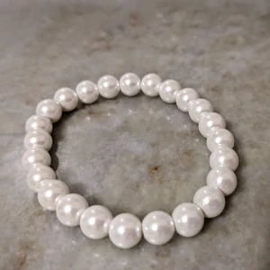 Vitt pärlarmband - Elegant vitt pärlarmband med klassiska runda pärlor. Perfekt för att ge en sofistikerad touch till din stil. Stretchigt och bekvämt att bära.