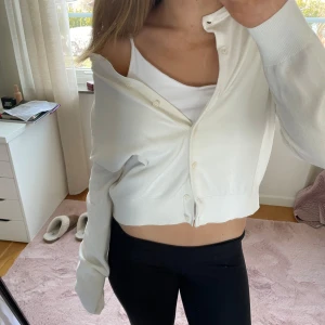 Vit kofta - Säljer en stilren vit kofta med knappar framtill. Perfekt för en avslappnad look. Koftan har långa ärmar och en mjuk känsla.stoelek XL men passar som M/L