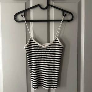 Randig ribbad linnetopp - Säljer en stilren svartvit randig ribbad linnetopp med smala axelband. Perfekt för varma dagar eller som ett lager under en jacka. 