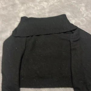 Svart stickad polotröja - Snygg svart stickad tröja utan axlar. Perfekt för en stilren look. 