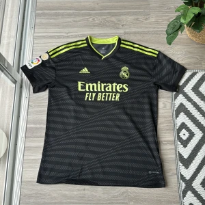 Real Madrid ställ 2022/23 - Real Madrid tröja   Köpte tröjan då den kom ut och jag gillade Vinicius Jr  Knappast använd  Storlek XL men sitter lite tajtare så skulle säga att den sitter som L 
