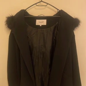 Svart kappa från Chiara Forthi - Elegant svart kappa från Chiara Forthi med päls på luvan. Den är i väldigt bra skick och är skit snyggt! Säljer denna för det inte kommer till användning💕