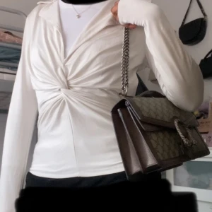 Vit tie knot blus med krage - Silkig V-ringad blus från Nelly med krage och tie knot i mitten, har en liten fläck som ej syns från långt håll. Pris kan diskuteras vid snabb affär 😊