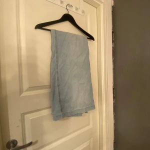 Ljusblå jeanskjol - Säljer en ljusblå jeanskjol med klassisk design. Kjolen har en rak passform och är perfekt för en avslappnad stil. Den är tillverkad i ett mjukt denimtyg som ger en bekväm känsla.