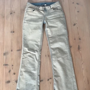 Ljusblå jeans från H&M Divided - Snygga ljusblå jeans från H&M Divided med en klassisk femficksdesign. Byxorna har en bootcut-stil och är perfekta för en avslappnad look. De har knappar och dragkedja framtill samt dekorativa bakfickor med knappar.
