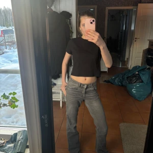 Grå jeansbyxor - Säljer ett par grå jeansbyxor med en klassisk straight passform. Byxorna har en mid waist och är perfekta för en avslappnad stil. De har en enkel design med fickor fram och bak.